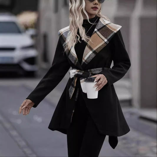 Woman in a black coat with plaid accents walking on a street.