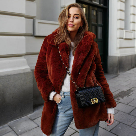 Woman wearing a brown fur coat with a black handbag on a city street.