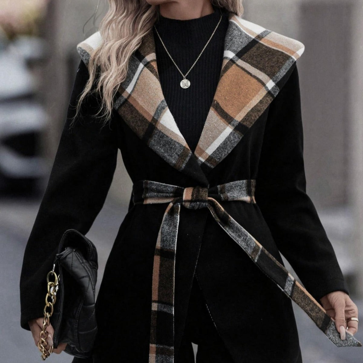 Person wearing a black coat with a plaid collar in an urban setting