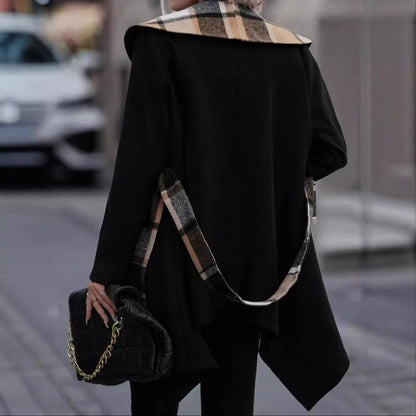 Person wearing a black coat with plaid collar and carrying a black handbag on a blurred street background