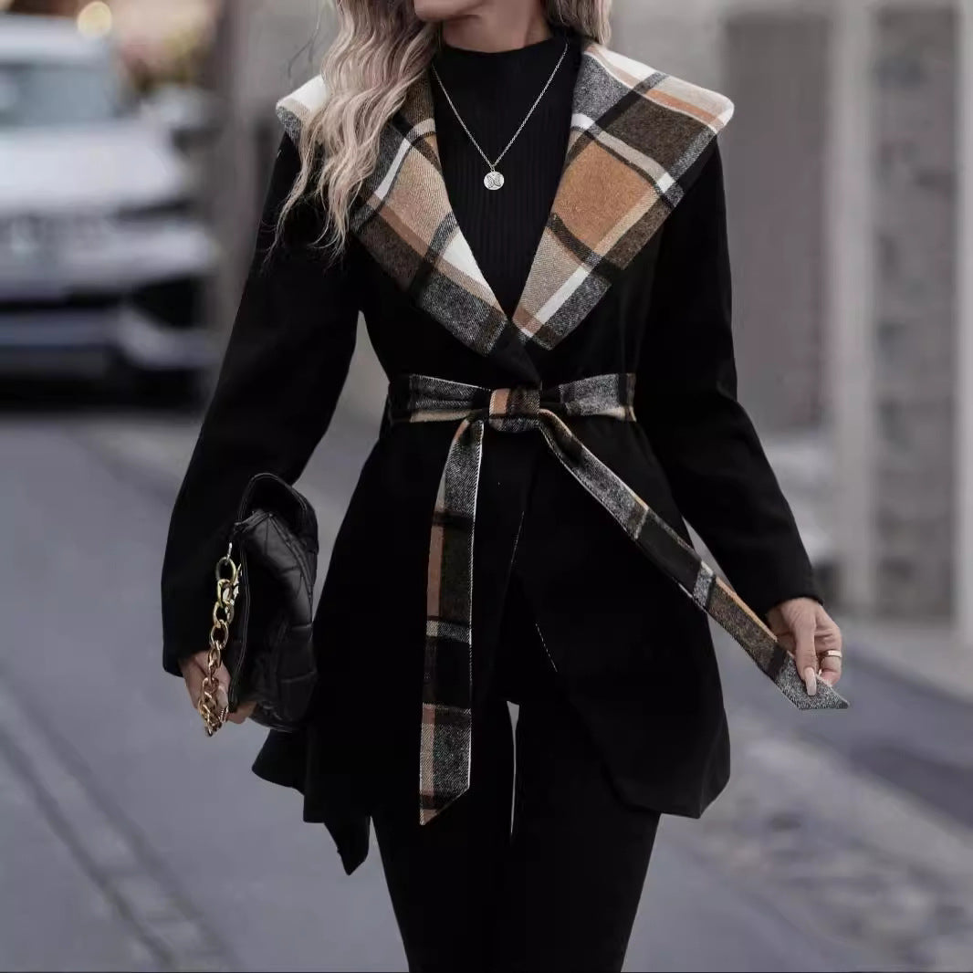 Person wearing a black coat with plaid accents on a city street