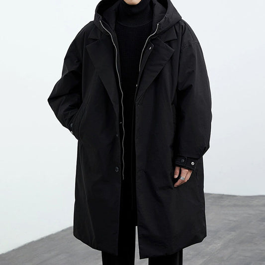 Person wearing a black coat against a white background