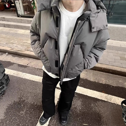 Person wearing a gray hooded jacket on a street.