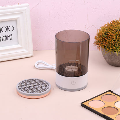 Humidifier on a table with a photo frame, plant, and makeup palette in the background.