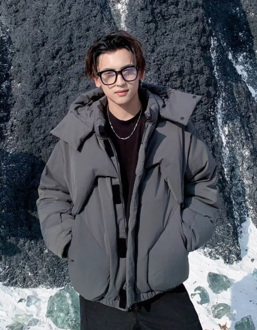 Person wearing a gray jacket standing in front of a rocky background