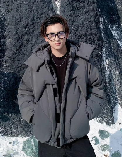 Person wearing a gray jacket standing in front of a rocky background