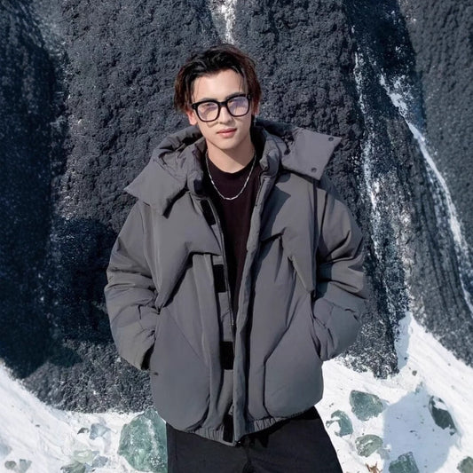 Person wearing a gray jacket standing in front of a snowy landscape with a waterfall.